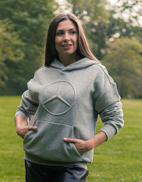 Abgebildet ist eine Frau, die einen hell grauen Mercedes-Benz Pullover mit Sternlogo trägt.