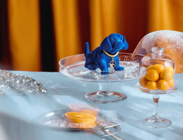 Mercedes-BZu sehen ist der blaue Wackeldackel auf einer Glasplatte in nostalgischer Inszenierung mit stilvollen Accessoires für Classic Fans und Sammler.