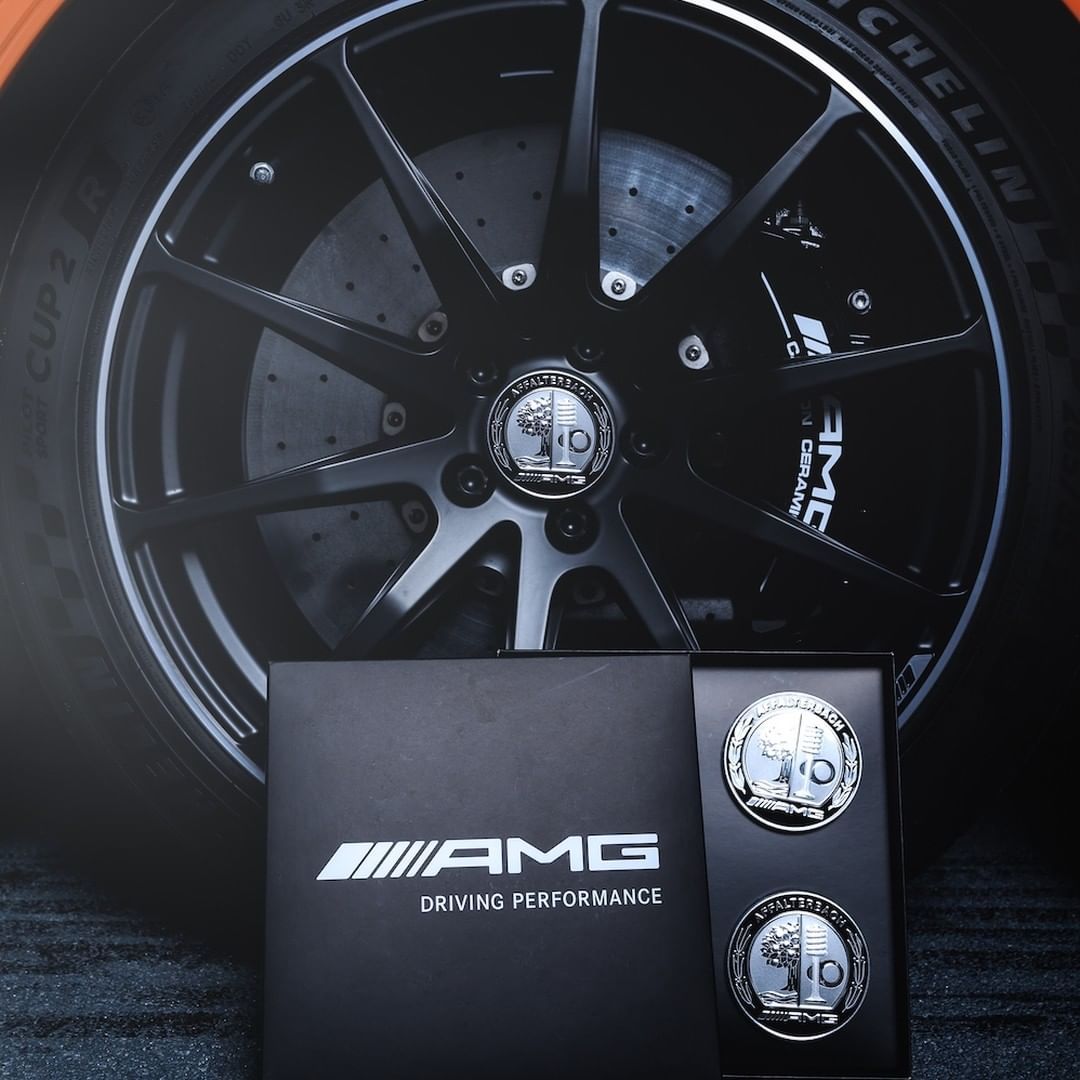 Schwarze AMG-Felge mit einem Radnabenabdeckungs-Set A0004001600. Das Bild verlinkt auf die Kategorie: Räder Zubehör.