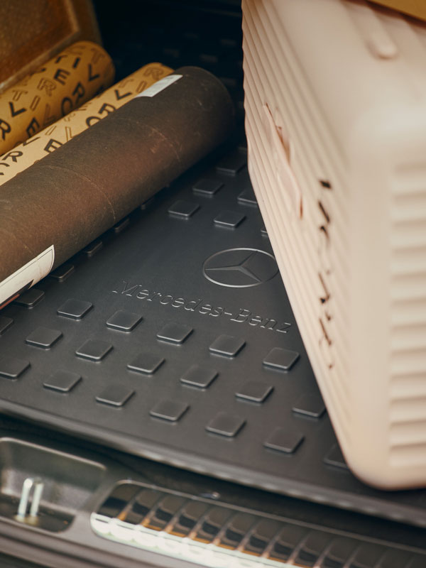 Im Bildausschnitt liegt eine Mercedes-Benz Kofferraumwanne im Kofferraum. Dieser wurde beladen mit einem beigen Koffer und mehreren Papprollen.