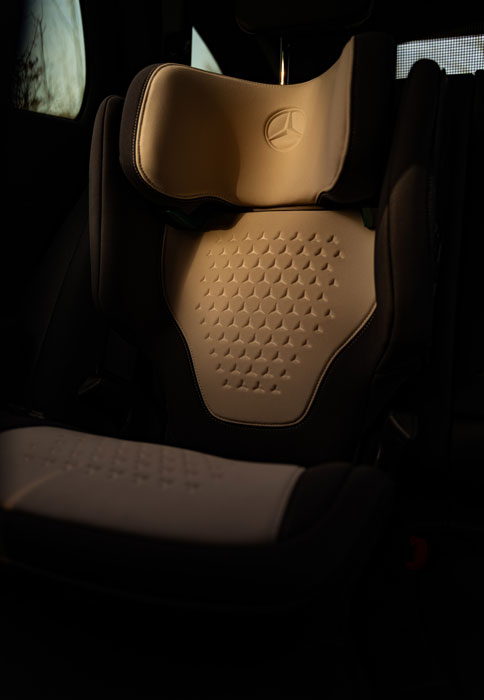 Abgebildet ist der Mercedes-Benz Kindersitz KIDFIX, M i-SIZE mit beigen Bezug auf der Rückbank des Autos.